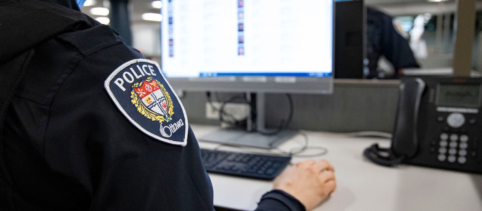 Un agent de police assis à un bureau devant un ordinateur. 