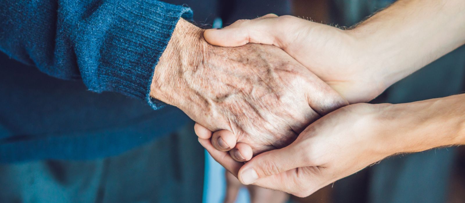 A young person holding an elderly person's hands. 
