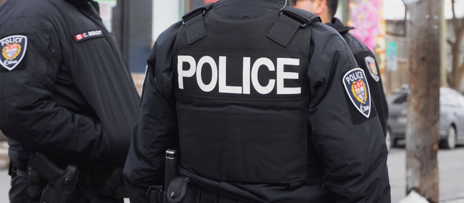 Un groupe de trois agents de la police d'Ottawa, debout à l'extérieur, en train de discuter.