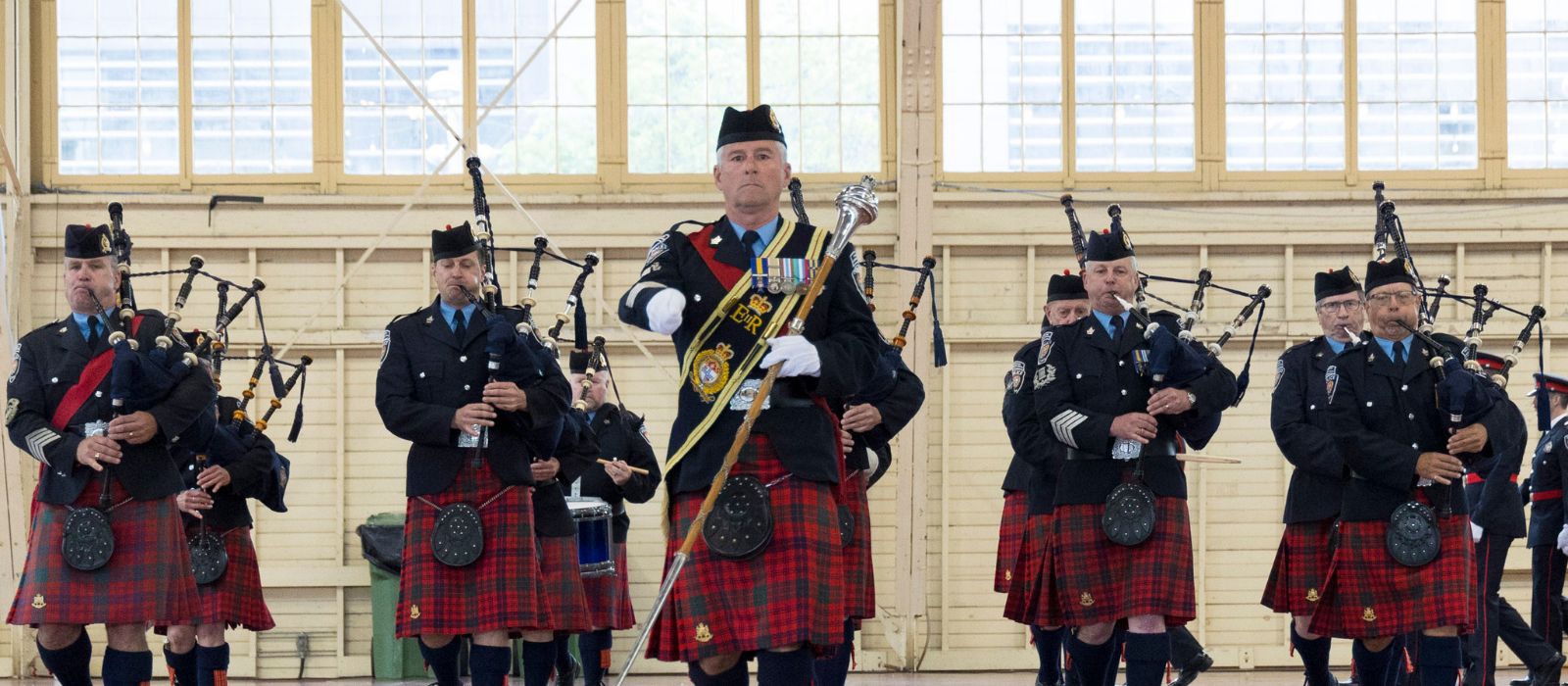 Le corps de cornemuses de la police d'Ottawa marchant et jouant de ses instruments lors d'un événement intérieur.